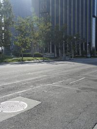 a person walking down a deserted city street with skyscrapers in the background in the daytime