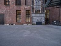 empty parking lot next to a brick building and parked bicycle racks along the side of the building