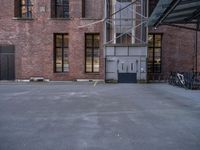 empty parking lot next to a brick building and parked bicycle racks along the side of the building