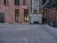 empty parking lot next to a brick building and parked bicycle racks along the side of the building