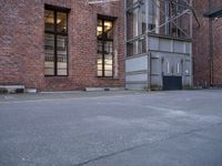 an empty parking lot near a tall brick building and a black fire hydrant on the sidewalk