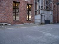 an empty parking lot near a tall brick building and a black fire hydrant on the sidewalk