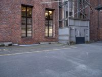 an empty parking lot near a tall brick building and a black fire hydrant on the sidewalk