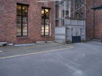 an empty parking lot near a tall brick building and a black fire hydrant on the sidewalk