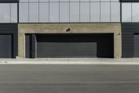 an empty street near a building with a garage on each side of the sidewalk and some windows on top of it