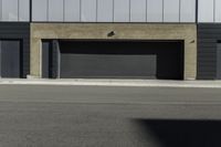 an empty street near a building with a garage on each side of the sidewalk and some windows on top of it