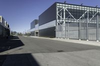 the large industrial building is empty on the sunny day on the street near cars parked in the parking lot