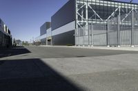 the large industrial building is empty on the sunny day on the street near cars parked in the parking lot