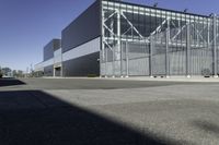 the large industrial building is empty on the sunny day on the street near cars parked in the parking lot