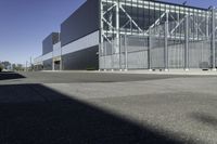 the large industrial building is empty on the sunny day on the street near cars parked in the parking lot