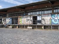 this is an image of a building with graffiti on the walls and benches on the street