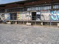 this is an image of a building with graffiti on the walls and benches on the street