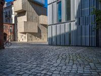 cobblestone driveway surrounded by modern buildings on sunny day with sun reflecting onto the windows