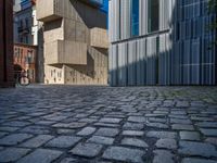 cobblestone driveway surrounded by modern buildings on sunny day with sun reflecting onto the windows