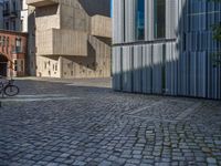 cobblestone driveway surrounded by modern buildings on sunny day with sun reflecting onto the windows