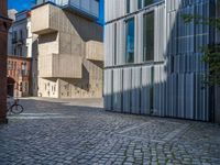 cobblestone driveway surrounded by modern buildings on sunny day with sun reflecting onto the windows