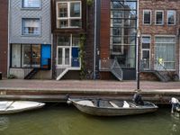 two boats sitting on top of a body of water near some buildings and stairs at the end of a brick pier