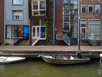 two boats sitting on top of a body of water near some buildings and stairs at the end of a brick pier