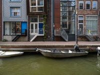 two boats sitting on top of a body of water near some buildings and stairs at the end of a brick pier