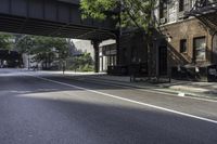 an empty street in the middle of downtown area with a bridge above it and a bicycle rack at the end