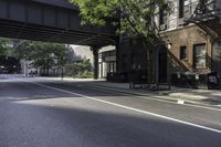 an empty street in the middle of downtown area with a bridge above it and a bicycle rack at the end