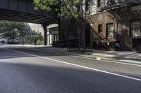 an empty street in the middle of downtown area with a bridge above it and a bicycle rack at the end