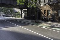 an empty street in the middle of downtown area with a bridge above it and a bicycle rack at the end