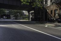 an empty street in the middle of downtown area with a bridge above it and a bicycle rack at the end