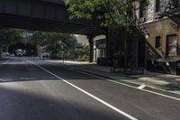 an empty street in the middle of downtown area with a bridge above it and a bicycle rack at the end