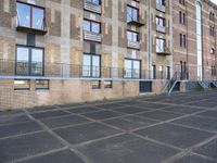 an empty parking lot in front of some buildings with ladders hanging from the side