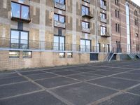 an empty parking lot in front of some buildings with ladders hanging from the side