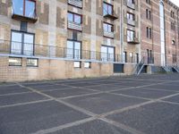 an empty parking lot in front of some buildings with ladders hanging from the side