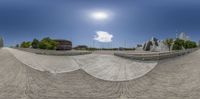 a fisheye lens reflects a skateboarder on the side of the ramp as another skateboarder stands in the distance