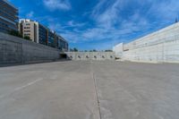 the empty parking lot in front of a wall with apartment buildings on it and a skateboarder on a ramp