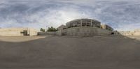 a round reflective object sits at the base of a building that stands next to a concrete road