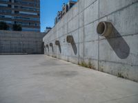 the empty parking lot in front of a wall with apartment buildings on it and a skateboarder on a ramp