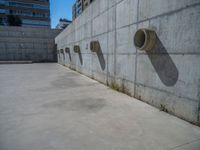 the empty parking lot in front of a wall with apartment buildings on it and a skateboarder on a ramp