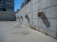 the empty parking lot in front of a wall with apartment buildings on it and a skateboarder on a ramp