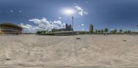 a view into a fisheye looking at the sky over a large building and playground