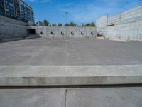 the empty parking lot in front of a wall with apartment buildings on it and a skateboarder on a ramp