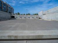 the empty parking lot in front of a wall with apartment buildings on it and a skateboarder on a ramp