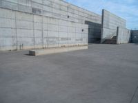 the empty parking lot in front of a wall with apartment buildings on it and a skateboarder on a ramp