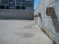 the empty parking lot in front of a wall with apartment buildings on it and a skateboarder on a ramp