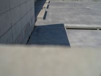 the empty parking lot in front of a wall with apartment buildings on it and a skateboarder on a ramp