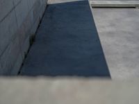 the empty parking lot in front of a wall with apartment buildings on it and a skateboarder on a ramp