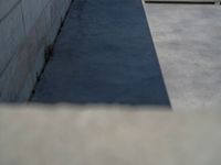 the empty parking lot in front of a wall with apartment buildings on it and a skateboarder on a ramp