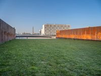 this grass field has been cut short to cover the area in the distance, and it is a grassy area next to an old building