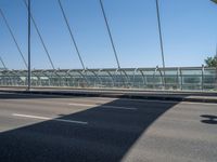 a truck driving across a bridge near a street corner near buildings and a bridge with many cables