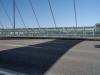 a truck driving across a bridge near a street corner near buildings and a bridge with many cables