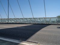 a truck driving across a bridge near a street corner near buildings and a bridge with many cables